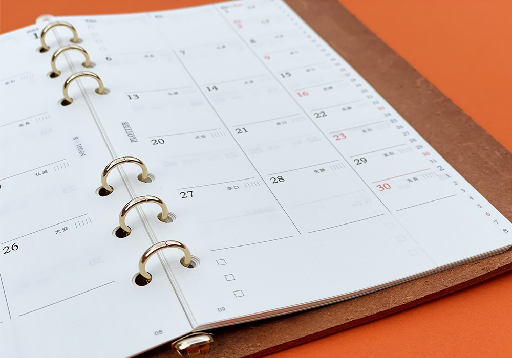 A PLOTTER Leather Binder opens to a monthly calendar.