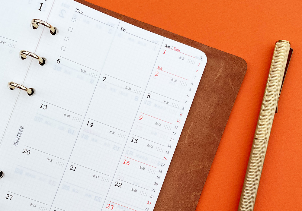 A PLOTTER Leather Binder opens to a monthly calendar.