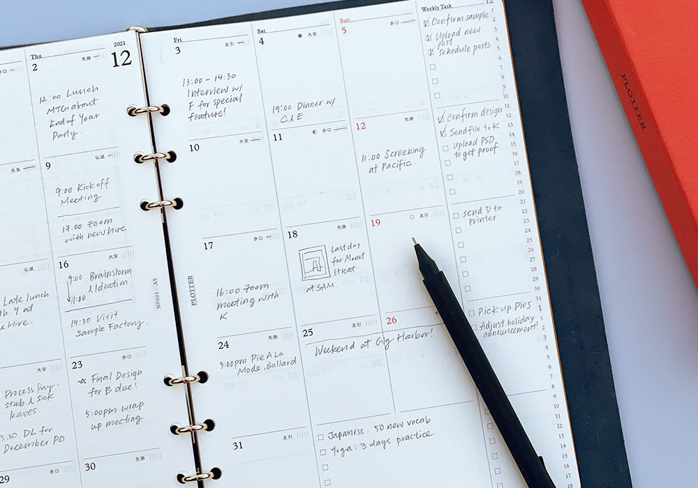 A close-up of a PLOTTER Leather Binder opened to a monthly schedule page.
