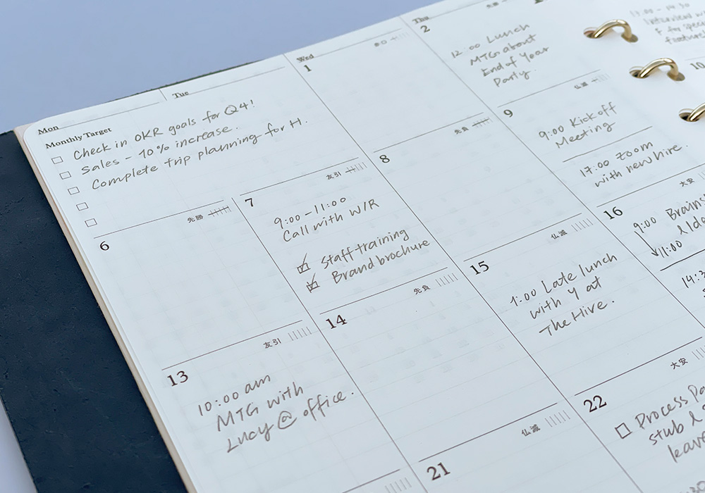 A close-up of a PLOTTER Leather Binder opened to a monthly schedule page.
