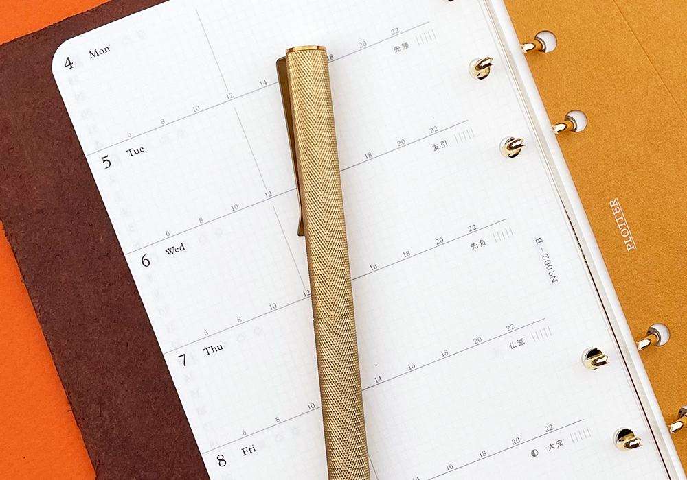 A PLOTTER Leather Binder opens to a weekly calendar.