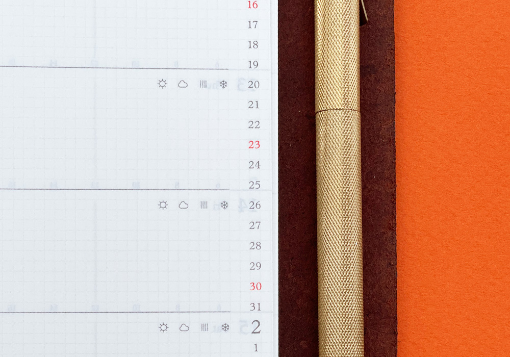 A close-up of a PLOTTER Leather Binder opened to a weekly schedule page.