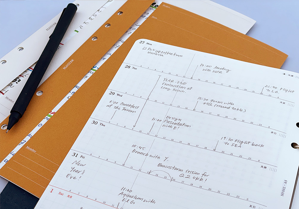 A PLOTTER Leather Binder open to a weekly calendar.