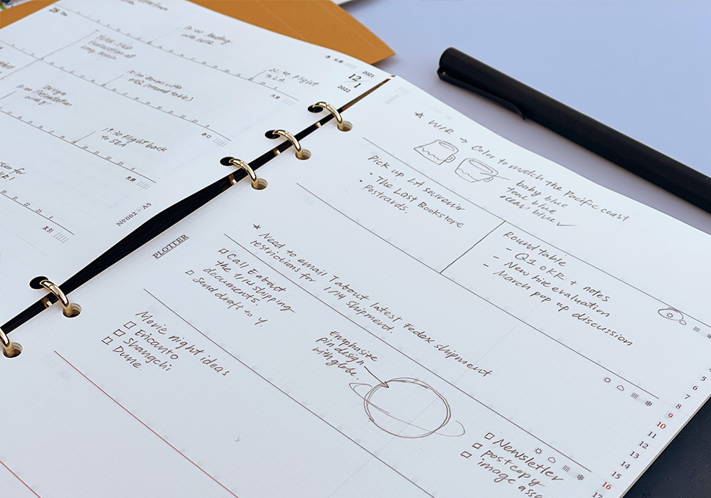 A PLOTTER Leather Binder open to a weekly calendar.