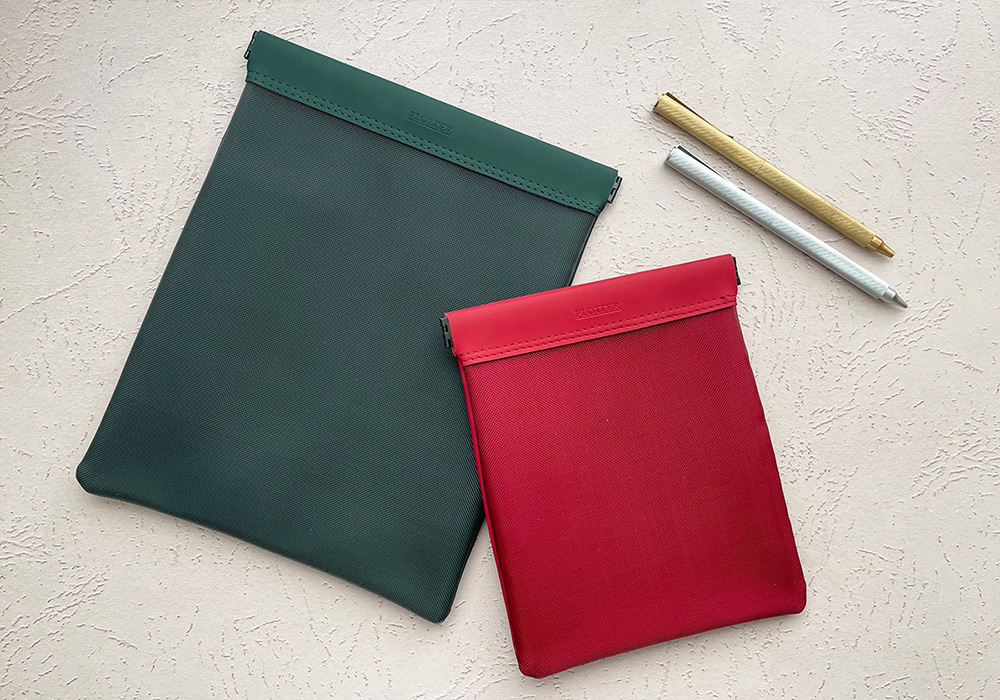 Two PLOTTER Mesh Cases side by side in green and red, next to two PLOTTER Pens in Silver and Gold.