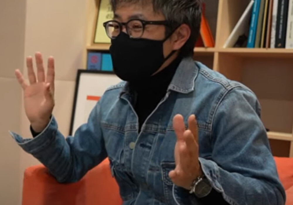 PLOTTER director Takayuki holding up both hands to explain the PLOTTER system.