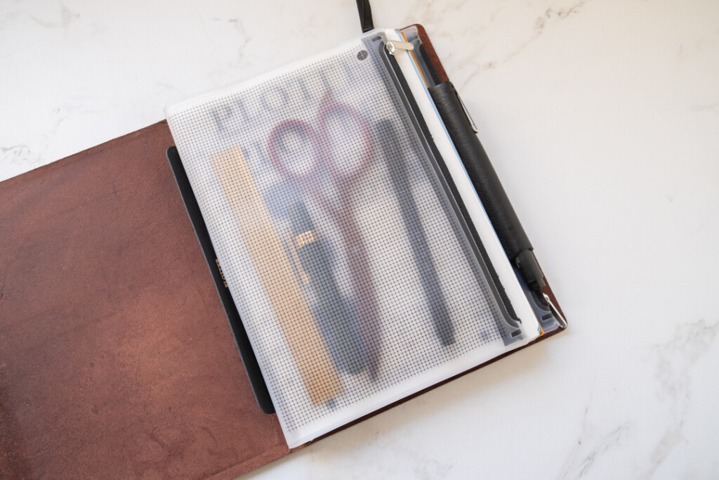 A PLOTTER in A5 Size with a fastener case holding a scissor, a fountain pen, a brass ruler, and a pen.