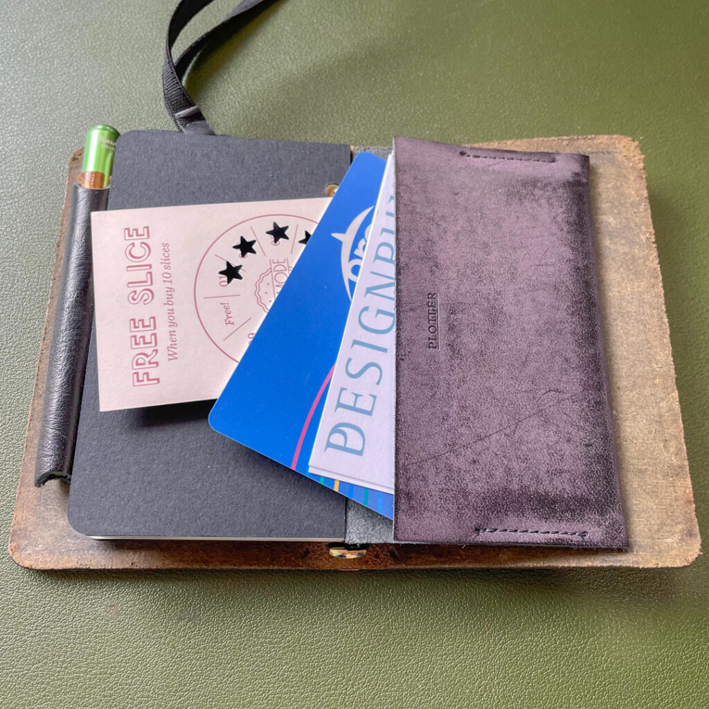A PLOTTER leather binder in Mini 5 Size holding transit cards, business cards, and punch cards.