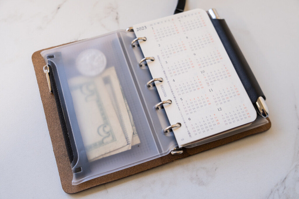 A PLOTTER Leather Binder in Mini 5 Size with a Diary Refill and a Fastener Case holding cash.