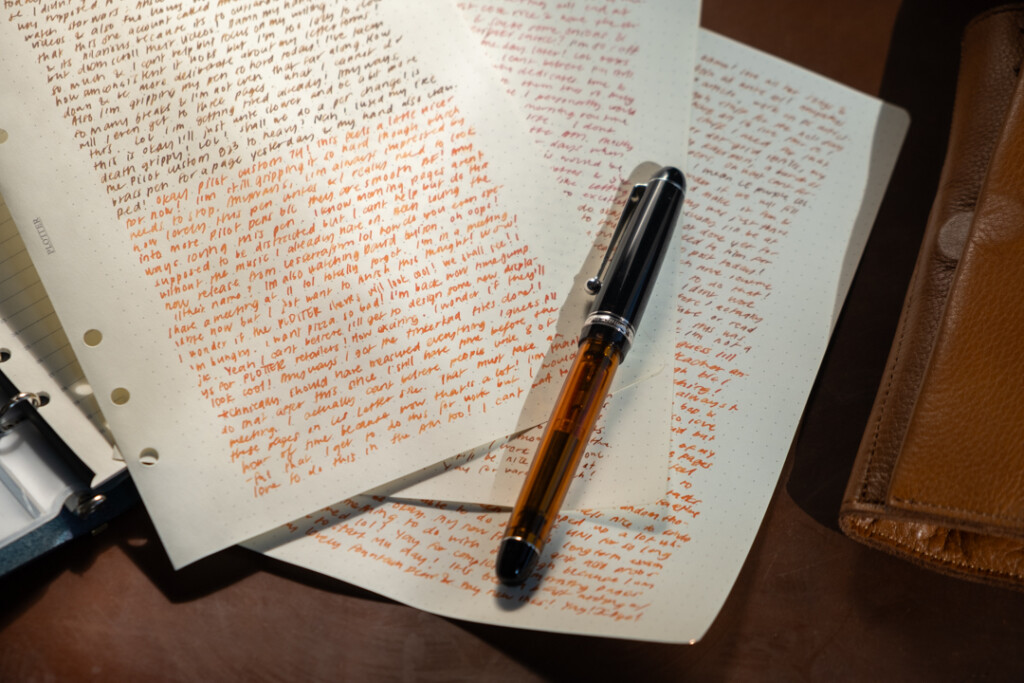 A fountain pen resting on three filled pages of PLOTTER in A5 Size featuring stream of conscious writing.