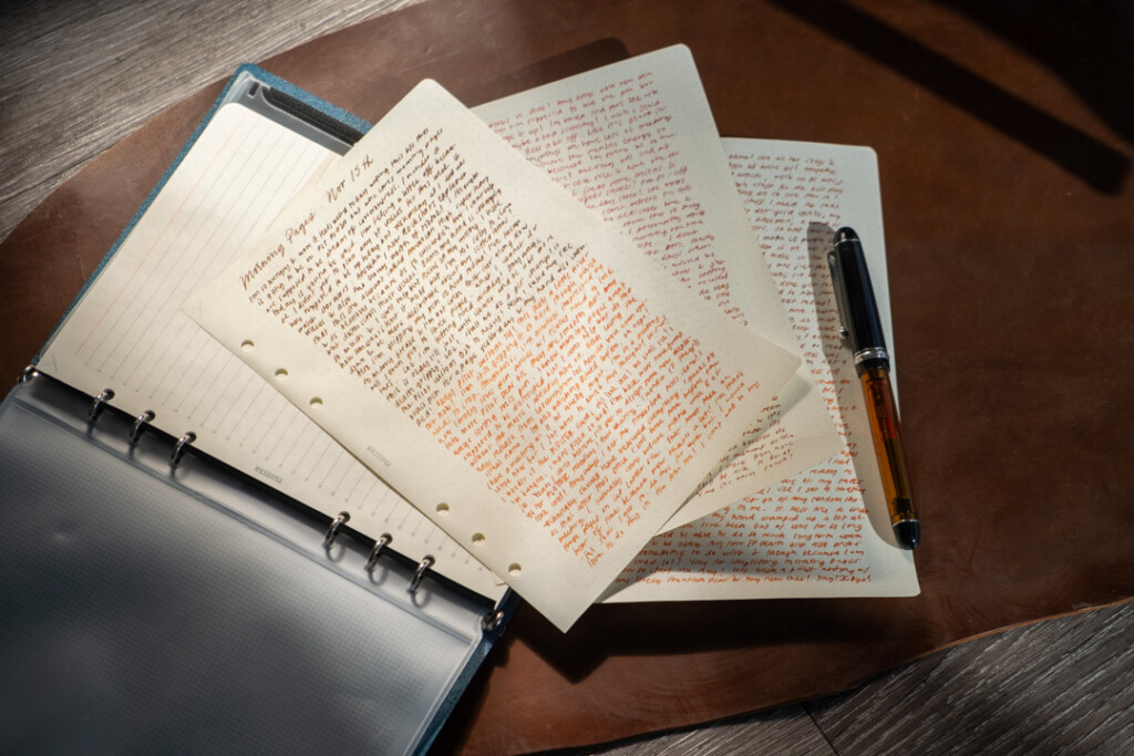 A fountain pen resting on three filled pages of PLOTTER in A5 Size featuring stream of conscious writing.