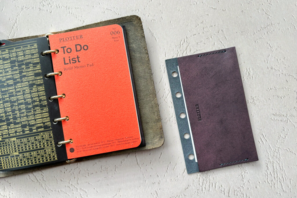 A PLOTTER Leather Binder in Mini 5 Size with a Limited Edition Purple Card Case next to it.