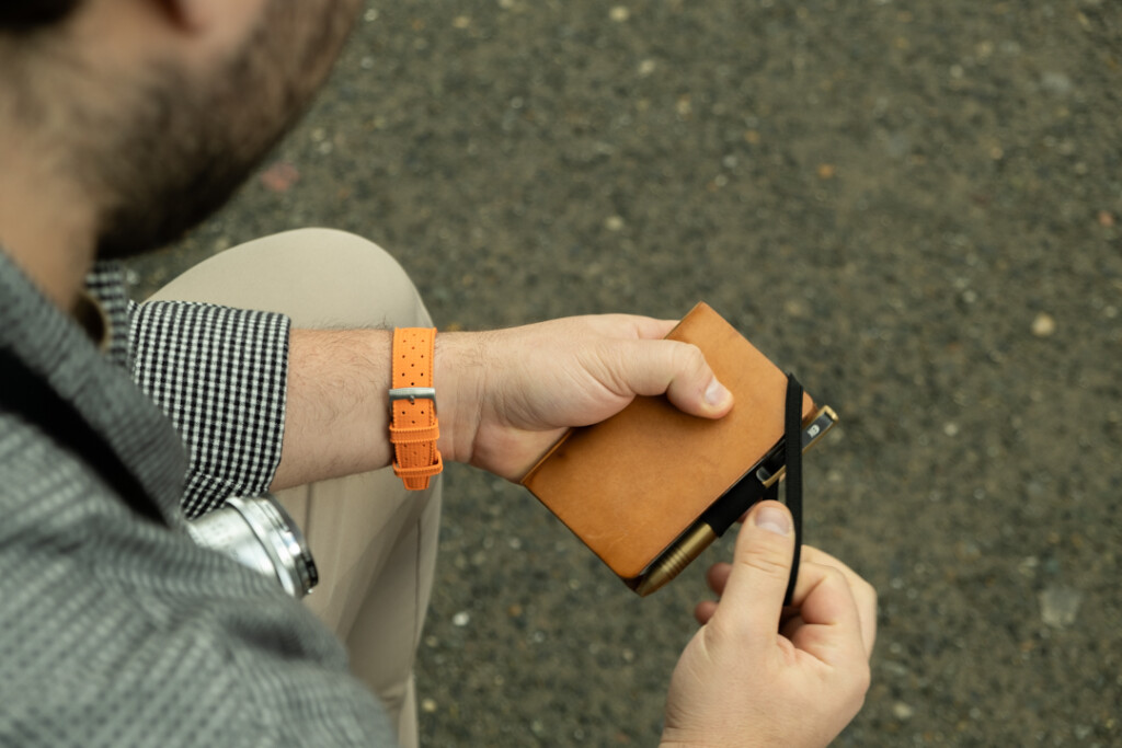 Chris Giannakos holding his PLOTTER Mini 5 leather binder as he tries to put the elastic closure on the binder.