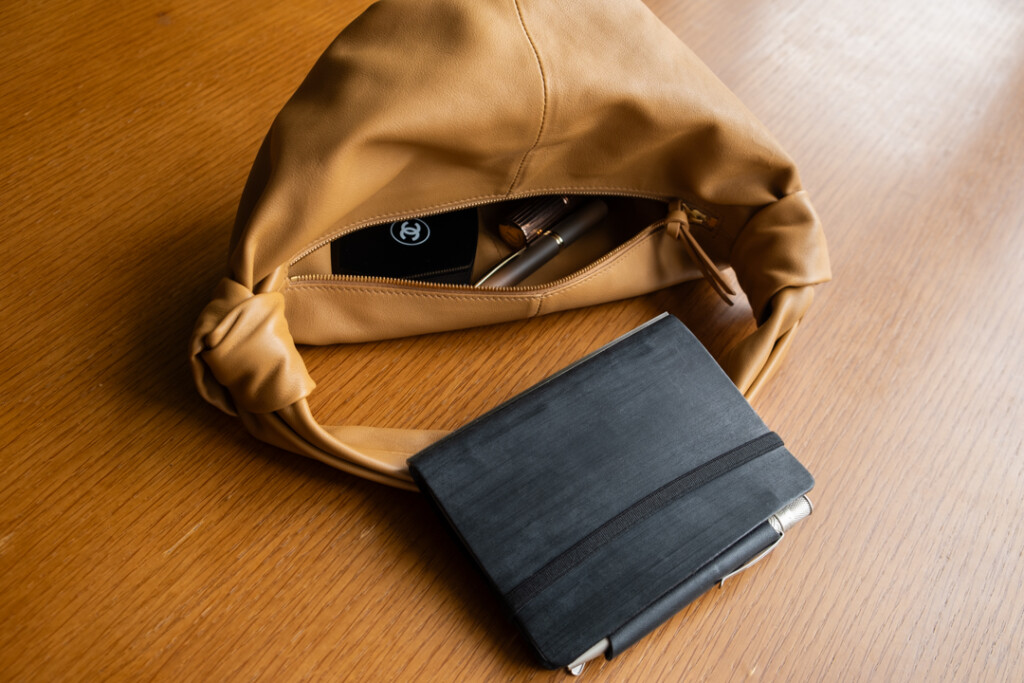 A PLOTTER Horse Hair II Mini Size Leather Binder beside a small tan purse.