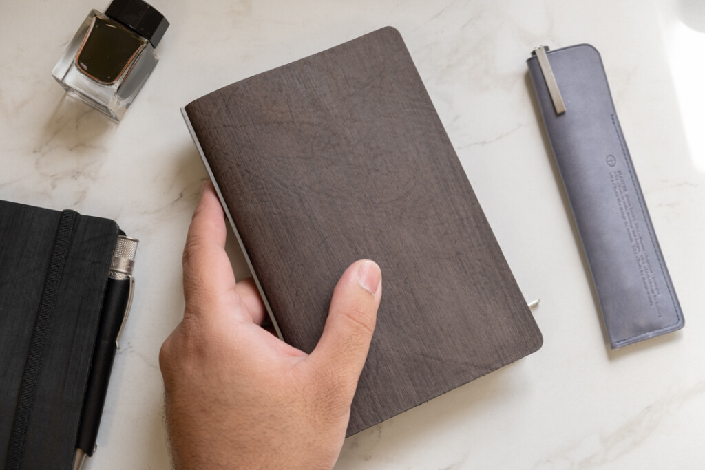 A person holding a PLOTTER Horse Hair II Leather Binder in gray.