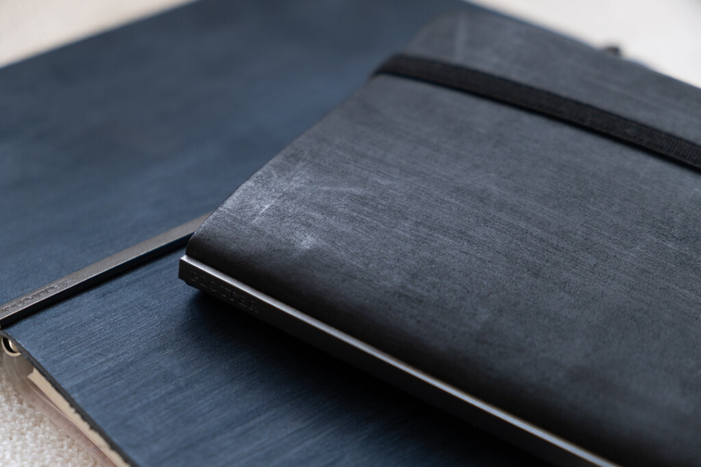 A close-up of PLOTTER Horse Hair II Leather Binder in navy blue and black.