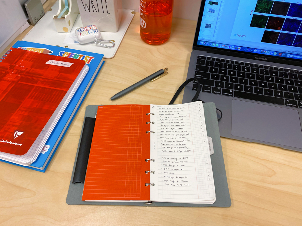 PLOTTER Bible Size is open on a desk with a laptop and clipboard beside it.