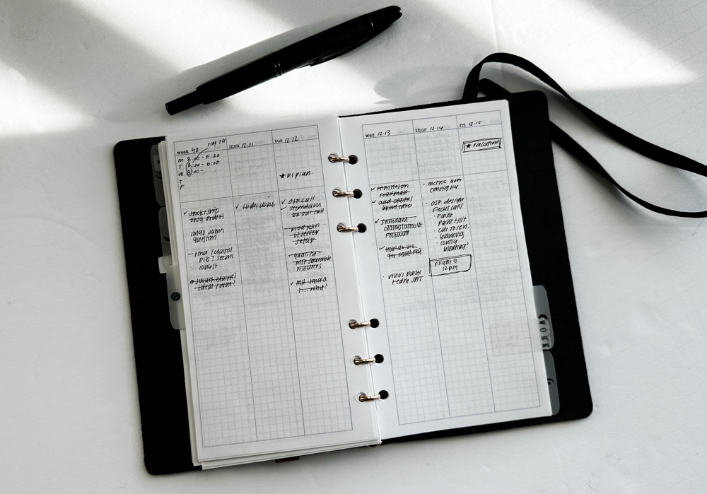 PLOTTER Bible Size Leather Binder open to a page with a weekly calendar.