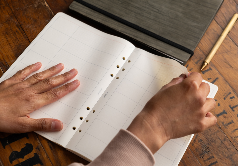 Hand tearing off a sheet of Chart Grid paper from from a PLOTTER Refill memo pad.