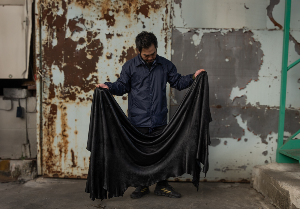 Leather Craftsman holding a piece of PLOTTER Shiranami leather.