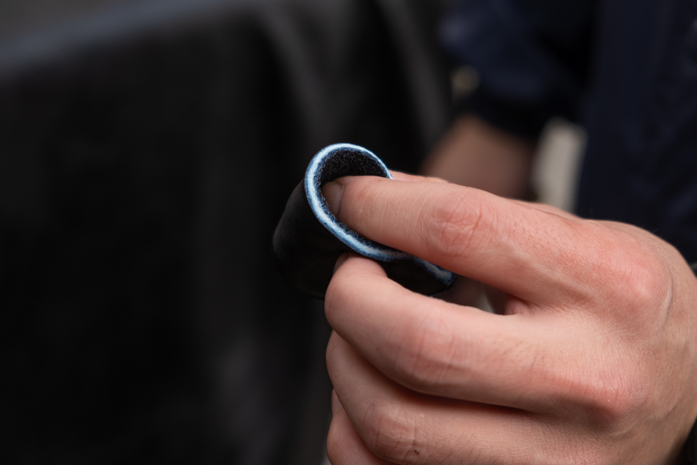 Leather craftsman showing cut piece of Shiranami leather to show the white core of the leather contrasting the blue indigo dye on the surface.