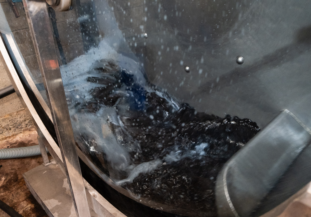 White leather in a dyeing drum that spins with indigo dye in it with warm water.