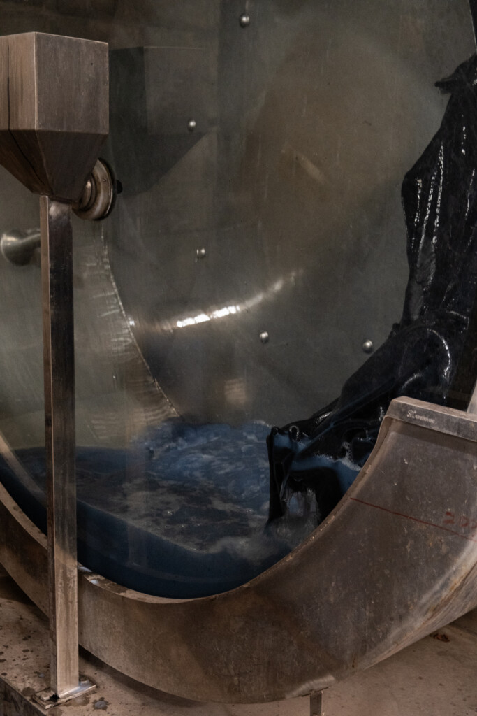 Indigo-dyed leather in a spinning dyeing drum in a blue dye solution.
