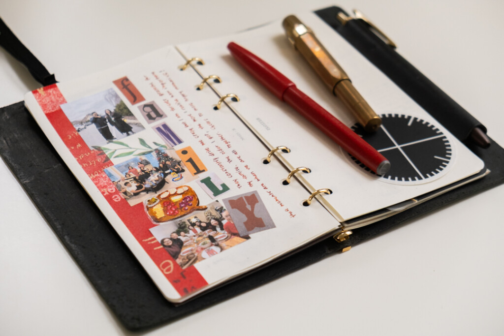 A PLOTTER Leather Binder open to a journal page about family and there is a pen and red marker on top of the right page in the PLOTTER.