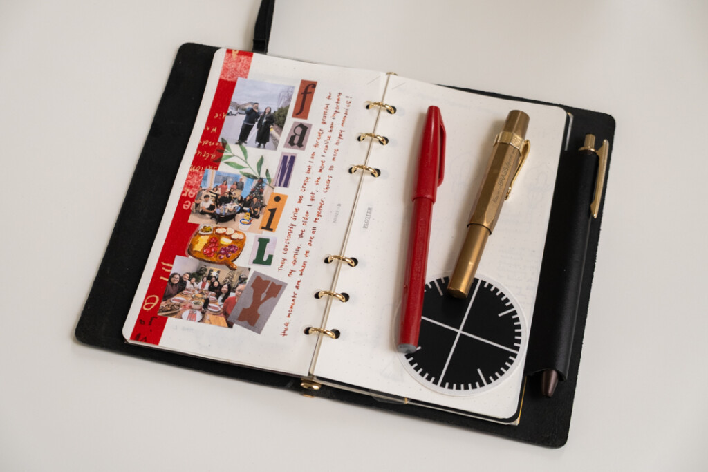 A PLOTTER Leather Binder open to a journal page about family and there is a pen and red marker on top of the right page in the PLOTTER.