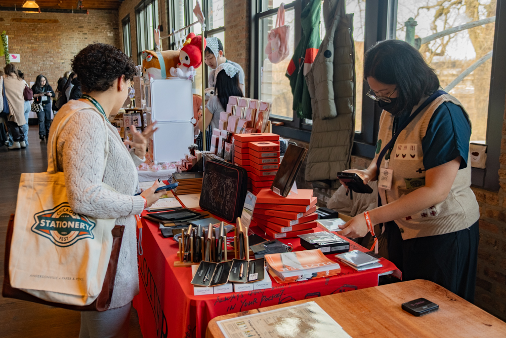 Person shopping at the PLOTTER USA table at Chicago Stationery Fest 2025.
