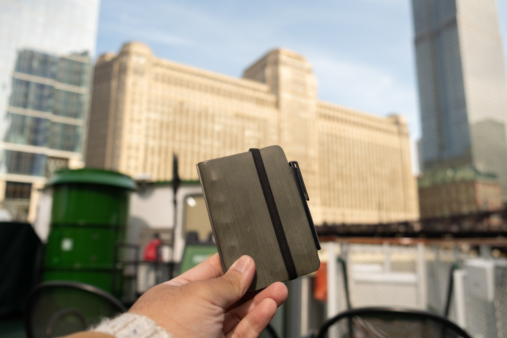 A person holding a PLOTTER Mini 5 in front of the downtown Chicago skyline.
