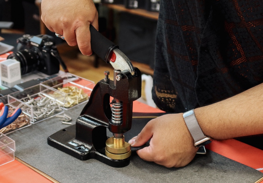 A person using the PLOTTER USA Hardware customization machine on a black PLOTTER leather binder. 