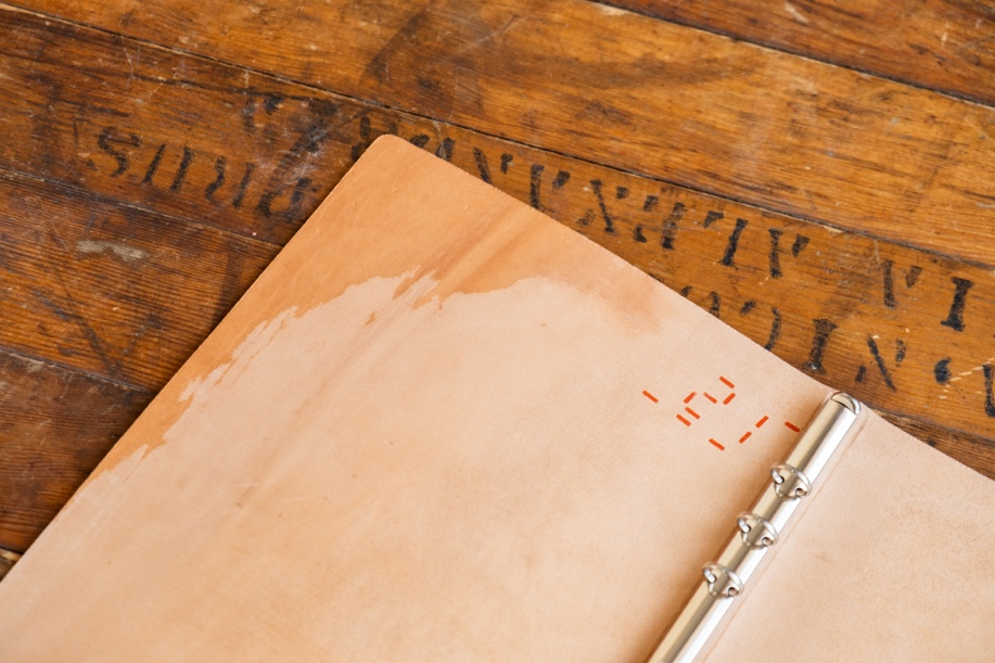 The inside of the Unevenly Dyed Cordovan Leather Binder on a wooden table.