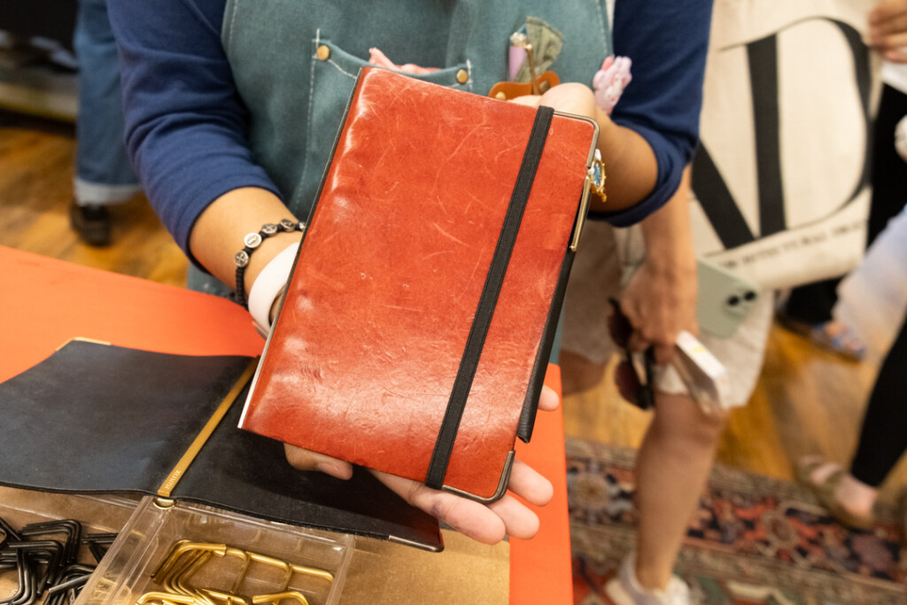 A customer showing off their Red PLOTTER Leather Binder at the Atlas Stationers sidewalk sale.