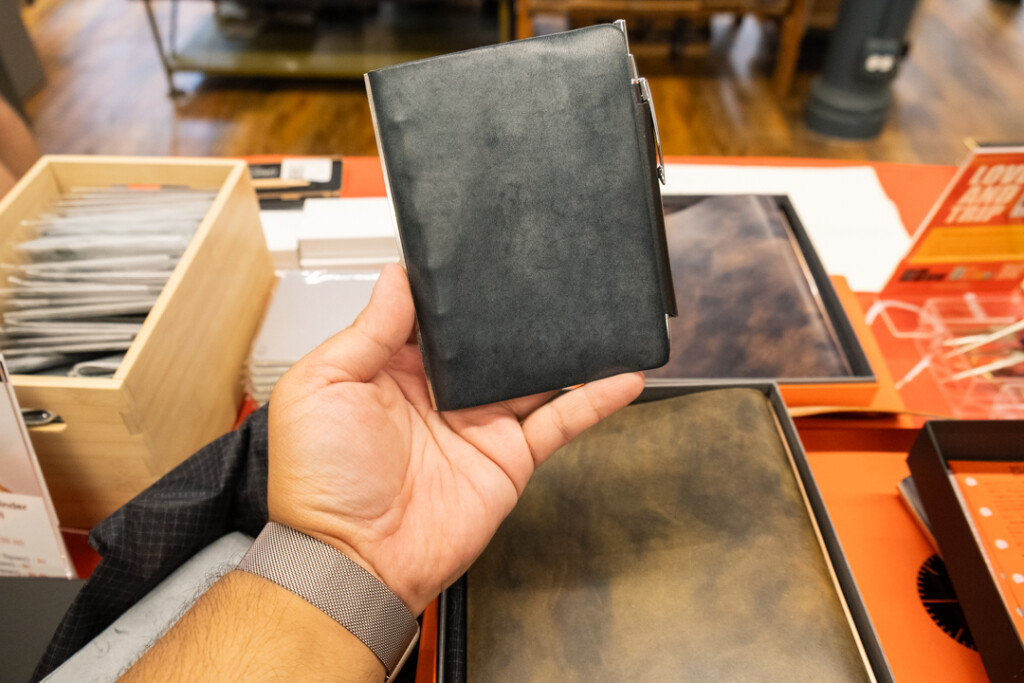 Person holding a PLOTTER Leather Binder in mini size in front of other leather binders.