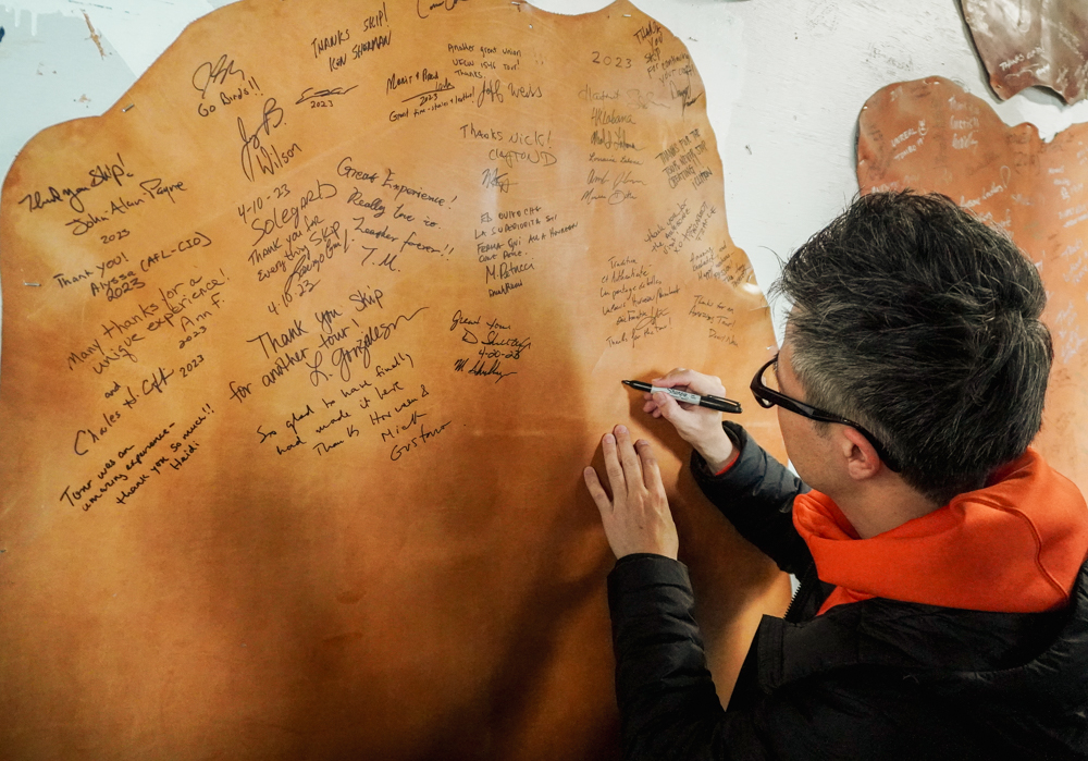 Photo of PLOTTER director Takayuki Saito leaving his signature in the heritage tannery. 