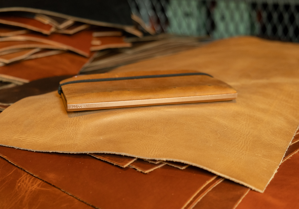 A Predator Amber Leather Binder in Narrow Size lying on a stack of leather swatches.