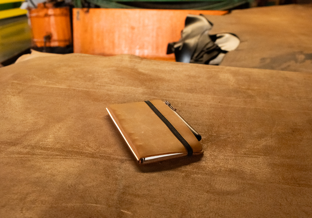 A PLOTTER leather binder in Predator Amber leather lying on top of a sheet of leather.