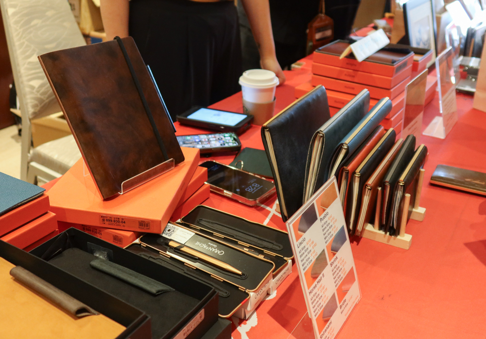Sample PLOTTER Leather Binders on a wooden rack and other PLOTTER products at the PLOTTER USA table at the SF Pen Show.
