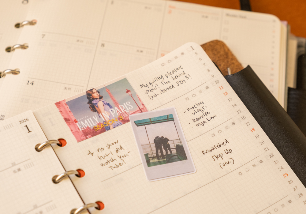 A person using the PLOTTER Diary 2026 Weekly Schedule to track what movie or show they watched on each day of the week.