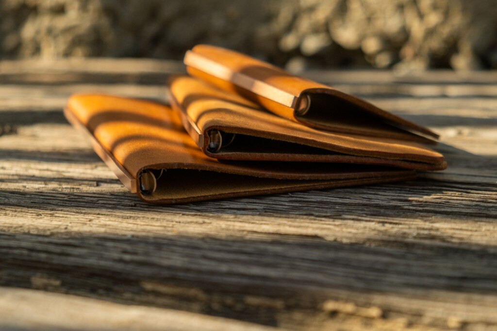 Three PLOTTER Leather Binders in Horween Predator Leather in Narrow Size, Bible Size and Mini 5 Size. All three binders are resting on a weathered wooden table.