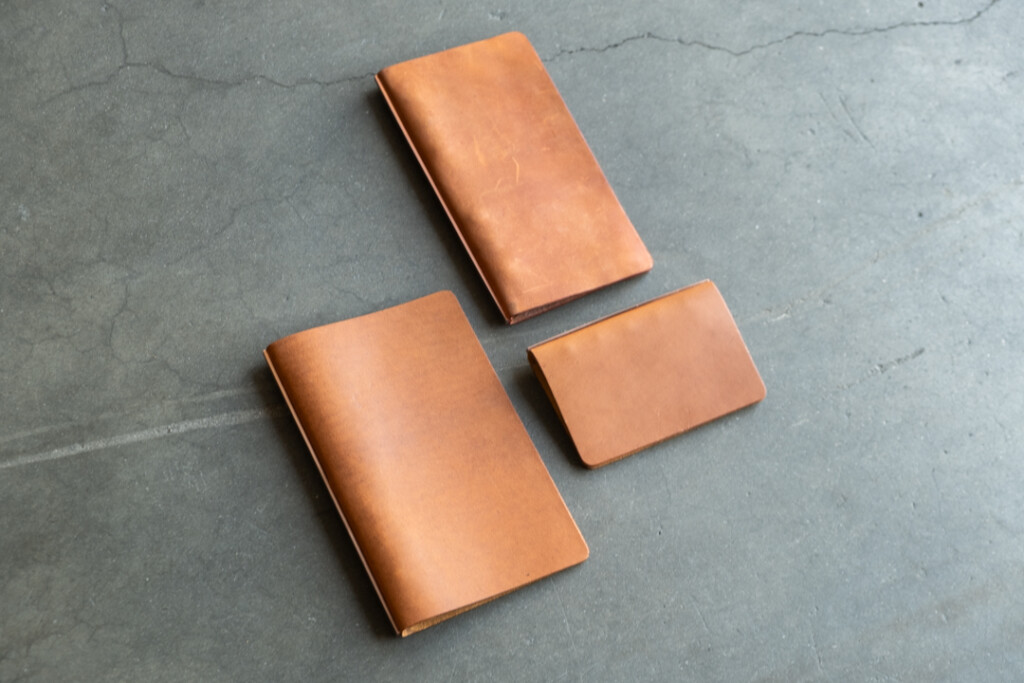 Three PLOTTER Leather Binders in Horween Predator Leather in Narrow Size, Bible Size and Mini 5 Size. All three binders are resting on concrete floor.