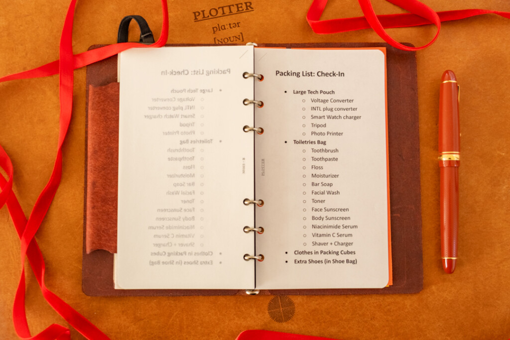 A PLOTTER Leather Binder open to a packing list. There are holiday decorations around the PLOTTER Leather Binder.