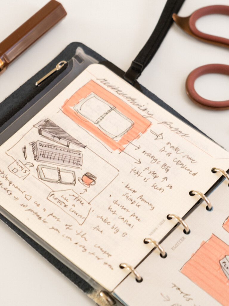 A photo of a PLOTTER Mini 5 Square open to some sketches and thumbnail drawings in pen and marker.