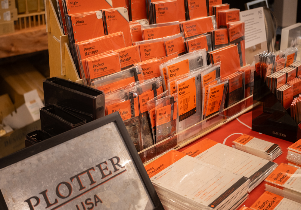 A close-up of a large wooden display filled with PLOTTER refill memo pads and accessories.