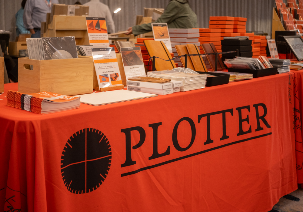 PLOTTER USA table filled with PLOTTER items, leather binders, and stationery at the California Pen Show.