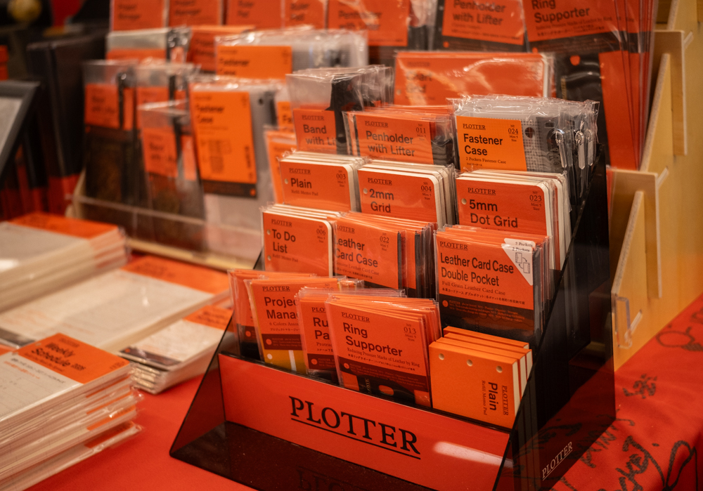 A small grey plastic display filled with PLOTTER refill memo pads and accessories for Mini 5 size leather binders.