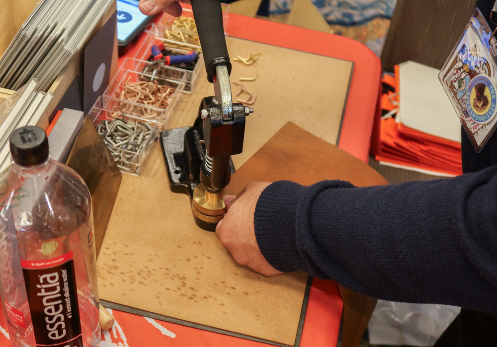 A craftsman putting corner hardware to the a PLOTTER Leather Binder at the PLOTTER USA table.
