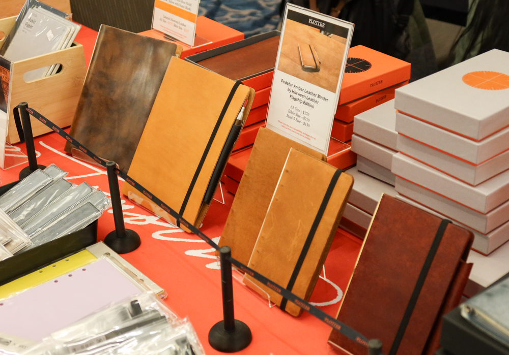 A close-up of the PLOTTER USA table showcasing the event-limited and PLOTTER USA-exclusive leather binders.