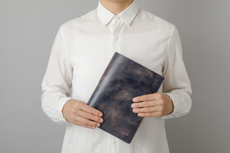 Man holding a blue Unevenly-dyed Cordovan Leather Binder in A5 Size.
